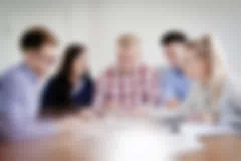 Gruppendiskussion Fünf Mitarbeiter sitzen zusammen an einem Tisch und diskutieren etwas