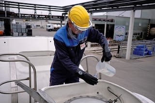 Employee drawing samples from a tanker