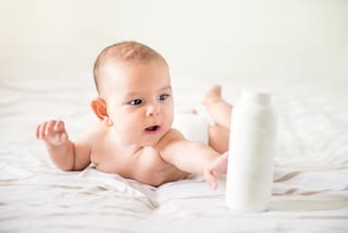 Baby holding a bottle of hand care lotion Baby holding a bottle of hand care lotion